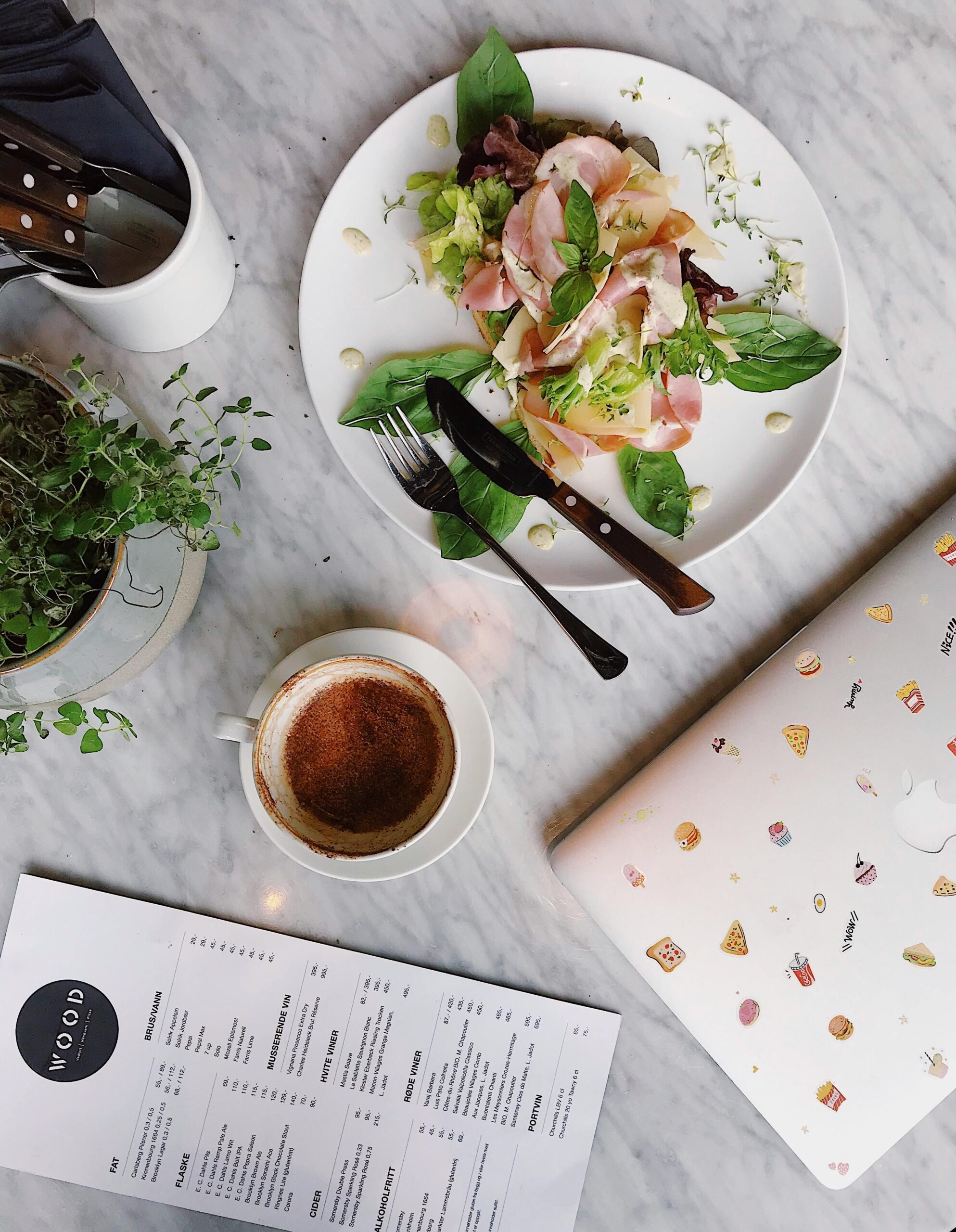 Top view of an elegant breakfast setup featuring coffee, fresh salad, and a laptop over a marble table.